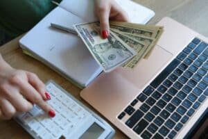 woman holding dollar bill and calculator