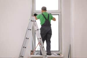 worker in uniform installing a window